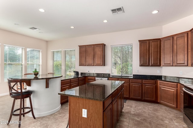 kitchen with a peninsula, a breakfast bar area, a kitchen island, and visible vents