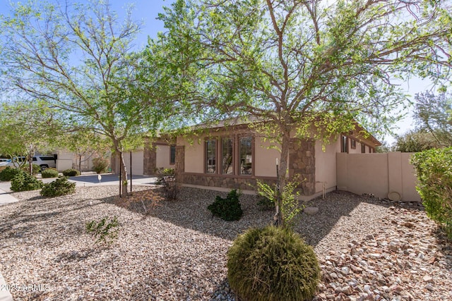 view of front of home with stucco siding, concrete driveway, fence, a garage, and stone siding