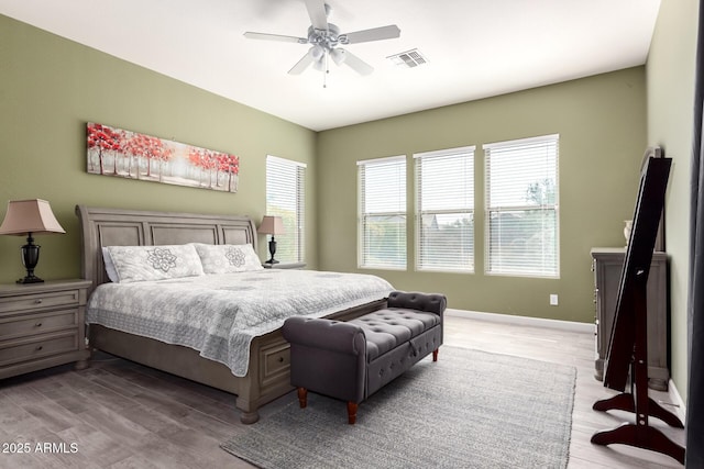 bedroom featuring a ceiling fan, visible vents, light wood-style flooring, and baseboards