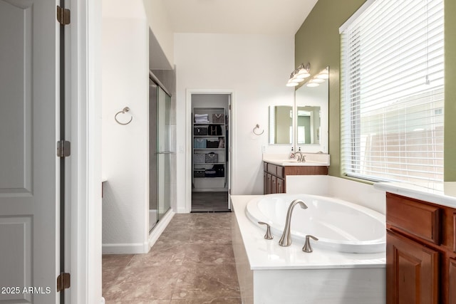 full bath featuring a stall shower, a spacious closet, vanity, and a bath