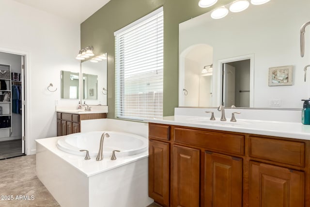 bathroom featuring a spacious closet, tile patterned flooring, vanity, and a bath