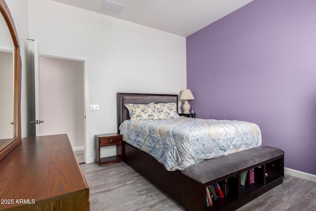 bedroom featuring baseboards, visible vents, and wood finished floors