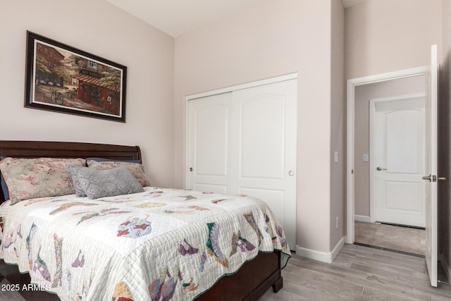 bedroom with light wood-type flooring, a closet, and baseboards