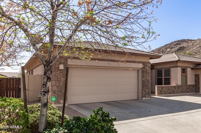 exterior space with an attached garage, fence, stone siding, driveway, and stucco siding