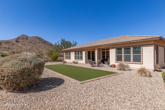 rear view of property featuring stucco siding, a mountain view, and a patio