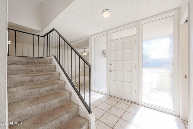 entryway with ceiling fan, light tile patterned floors, and a textured ceiling