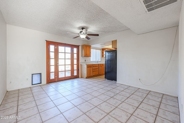 unfurnished living room with ceiling fan, light tile patterned flooring, and a textured ceiling