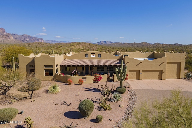 pueblo-style house with a garage and a mountain view