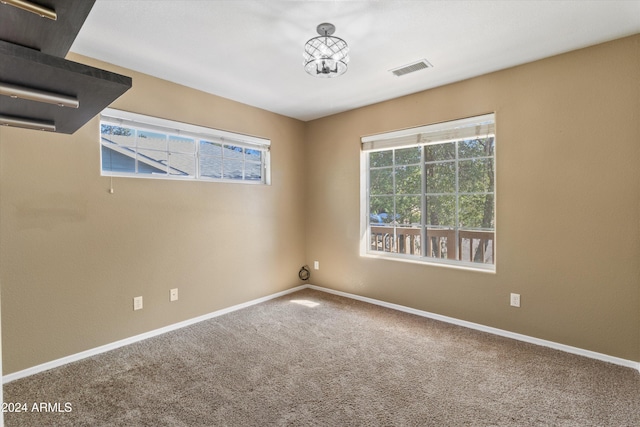 carpeted spare room with an inviting chandelier