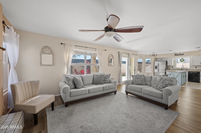 living room featuring a wealth of natural light, light hardwood / wood-style floors, ceiling fan, and sink