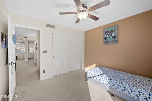 bedroom featuring ceiling fan, light carpet, and a closet