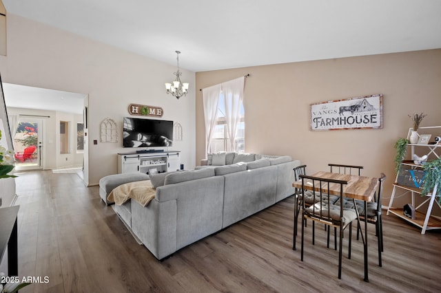 living room with hardwood / wood-style flooring, an inviting chandelier, and vaulted ceiling