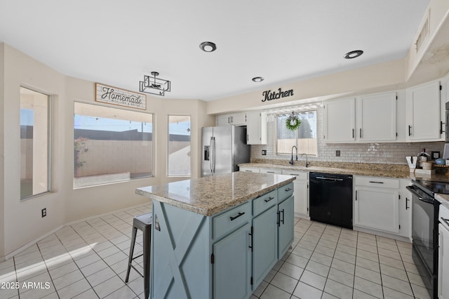 kitchen with black appliances, a center island, white cabinets, and light tile patterned floors