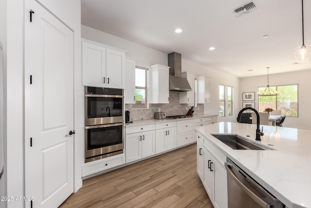 6356 S Granite St, Gilbert, AZ 85298 - kitchen with stainless steel appliances, a sink, wall chimney range hood, light countertops, and hanging light fixtures