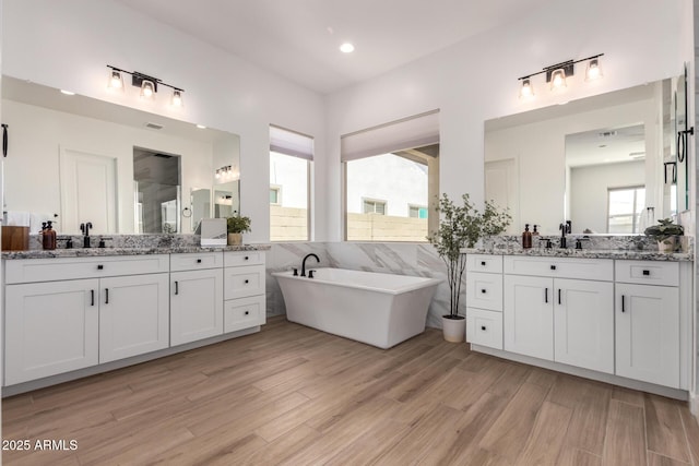 6356 S Granite St, Gilbert, AZ 85298 - bathroom with two vanities, wood finished floors, a soaking tub, and recessed lighting