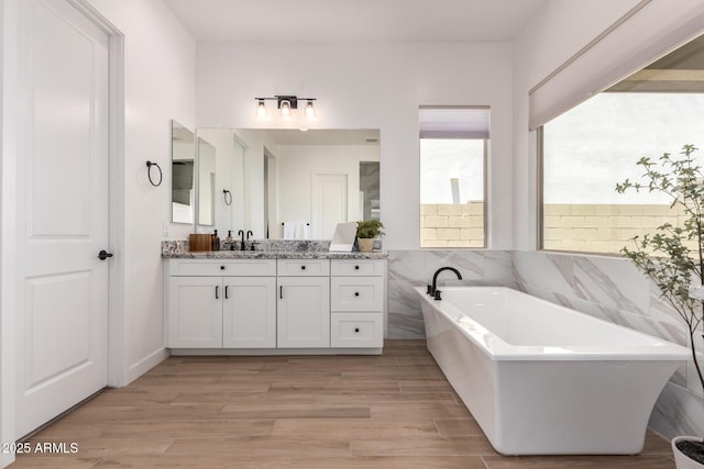6356 S Granite St, Gilbert, AZ 85298 - bathroom featuring vanity, a soaking tub, wood finished floors, and tile walls