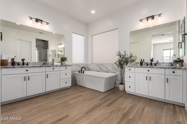 6356 S Granite St, Gilbert, AZ 85298 - bathroom with two vanities, wood finished floors, a freestanding bath, recessed lighting, and a shower