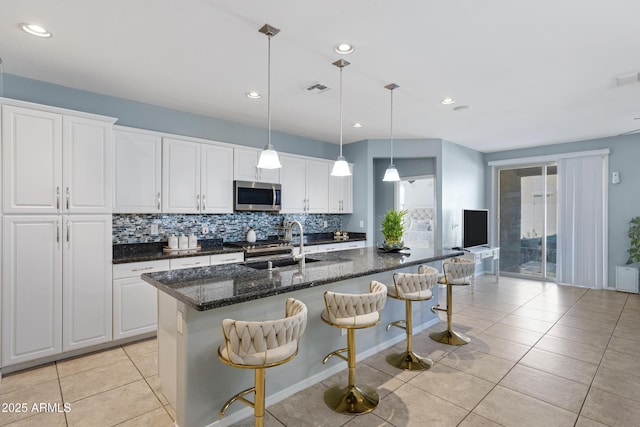 kitchen with white cabinetry, a kitchen island with sink, sink, and a kitchen breakfast bar