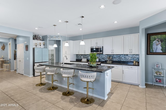 kitchen featuring appliances with stainless steel finishes, white cabinetry, an island with sink, sink, and light tile patterned floors