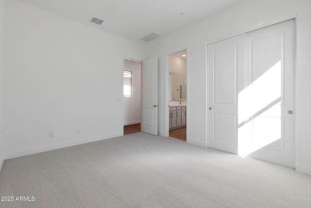 unfurnished bedroom featuring carpet floors, a closet, and ensuite bathroom