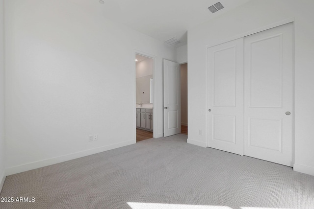 unfurnished bedroom featuring a closet, ensuite bathroom, and carpet floors