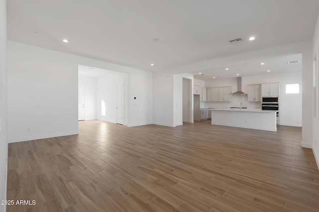 unfurnished living room featuring sink and light hardwood / wood-style floors