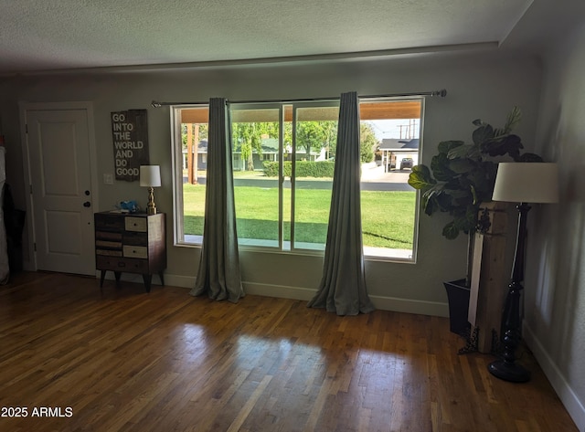 doorway to outside with a textured ceiling and dark wood-type flooring