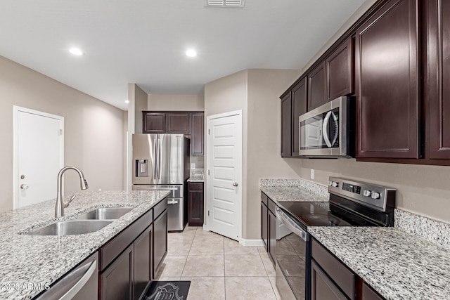 18800 W Madison St, Buckeye, AZ 85326 - kitchen featuring light stone counters, light tile patterned flooring, stainless steel appliances, a sink, and dark brown cabinets
