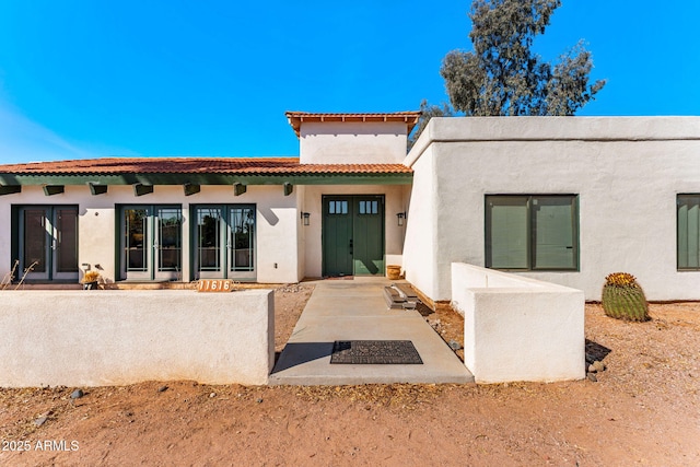 rear view of property featuring a tile roof and stucco siding