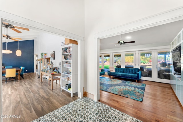 living area with a towering ceiling, french doors, wood finished floors, and a ceiling fan