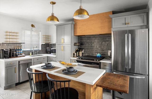 kitchen with sink, tasteful backsplash, decorative light fixtures, light tile patterned flooring, and stainless steel appliances