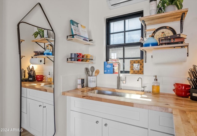 bar with an AC wall unit, sink, white cabinets, and wooden counters