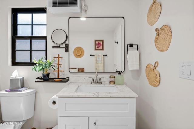 bathroom with vanity, toilet, and a wall unit AC