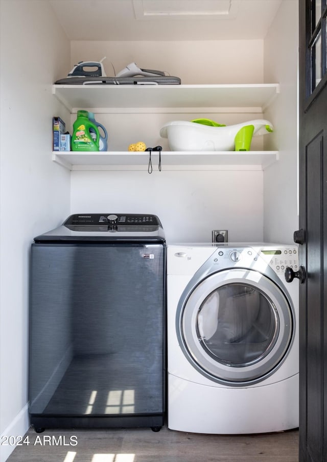 washroom with hardwood / wood-style flooring and washing machine and clothes dryer