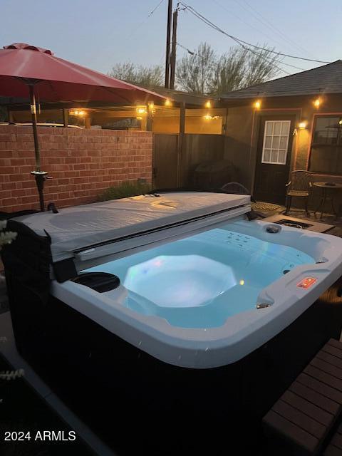 pool at dusk featuring a hot tub