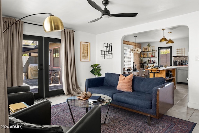 living room with french doors, tile patterned flooring, and ceiling fan with notable chandelier