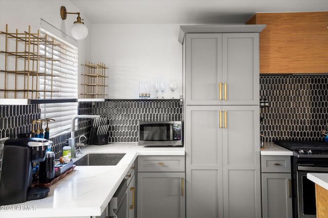 kitchen with gray cabinetry, sink, and stainless steel appliances