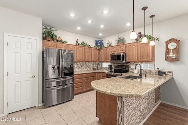 kitchen with sink, appliances with stainless steel finishes, tasteful backsplash, decorative light fixtures, and kitchen peninsula