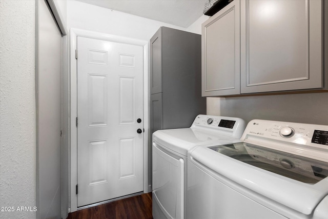 laundry room with cabinets, dark wood-type flooring, and washing machine and clothes dryer