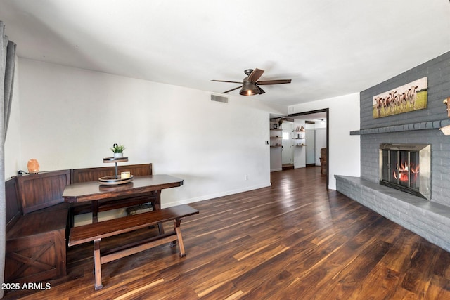 dining room with dark hardwood / wood-style floors, ceiling fan, and a fireplace