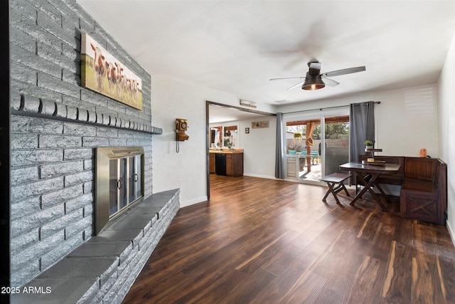 dining space with ceiling fan, a fireplace, and dark hardwood / wood-style flooring