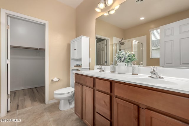 bathroom featuring vanity, toilet, a shower with shower door, and tile patterned flooring