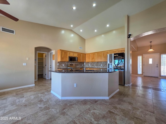 kitchen with appliances with stainless steel finishes, a sink, arched walkways, decorative backsplash, and visible vents