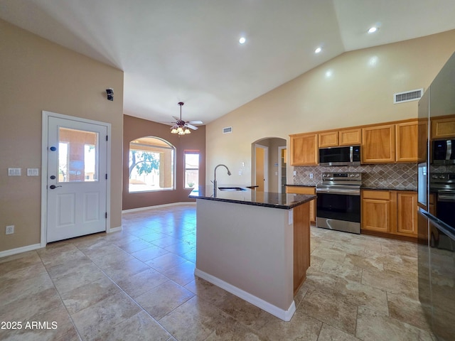 kitchen with visible vents, a sink, tasteful backsplash, arched walkways, and appliances with stainless steel finishes