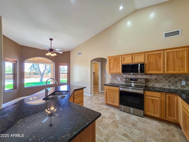 kitchen featuring visible vents, a sink, arched walkways, appliances with stainless steel finishes, and vaulted ceiling