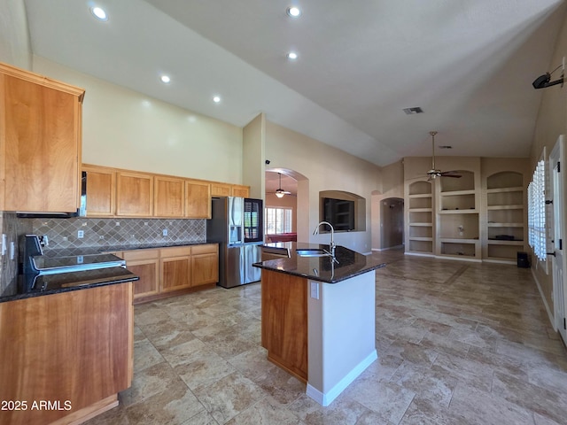 kitchen with a ceiling fan, electric range, stainless steel fridge, arched walkways, and a sink