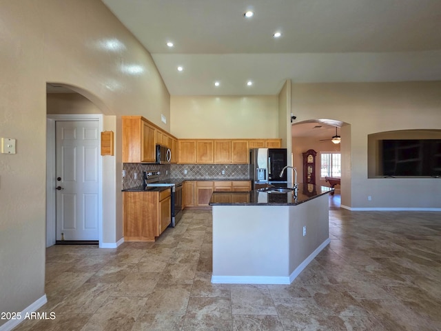 kitchen featuring a sink, arched walkways, high vaulted ceiling, stainless steel appliances, and backsplash