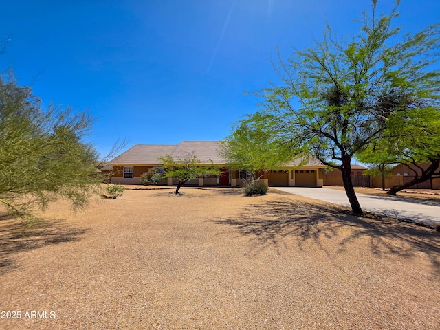 view of front facade with concrete driveway, an attached garage, and fence