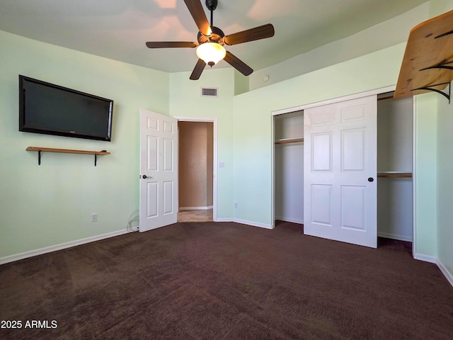 unfurnished bedroom featuring baseboards, a closet, dark carpet, and visible vents