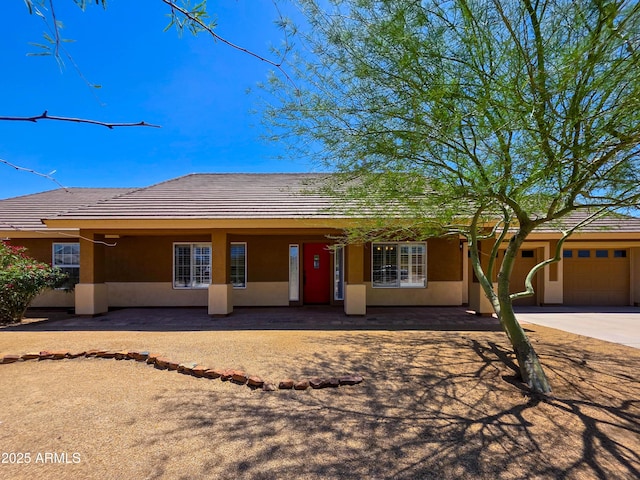 single story home with a garage, stucco siding, driveway, and a tile roof